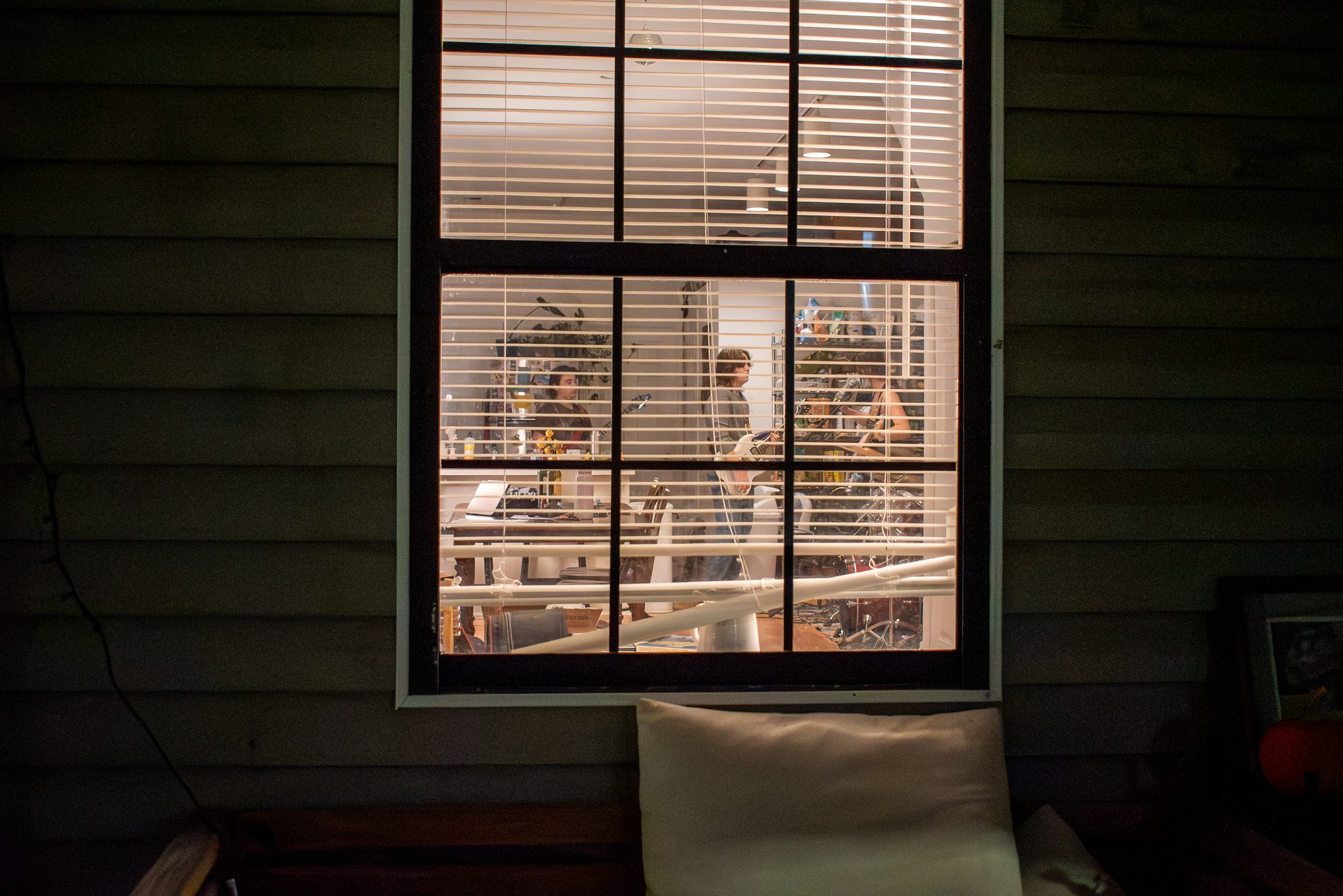 Band members can be seen through the front porch window of the house they practice at.