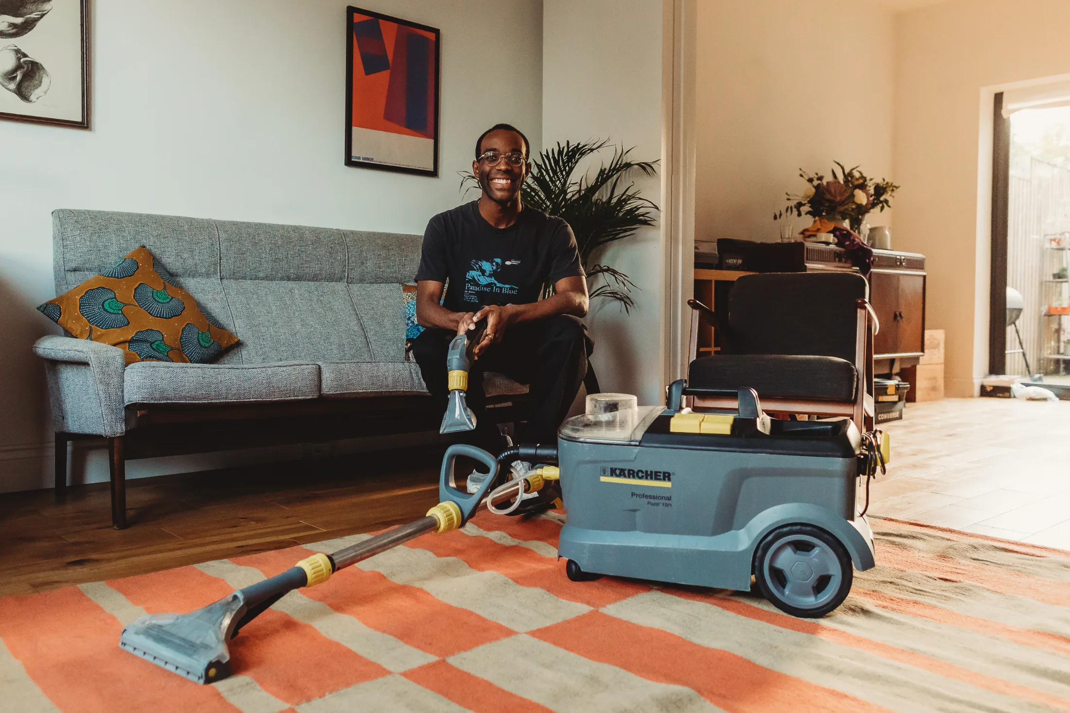 Hackney, UK. A borrower poses in his home with a vacuum that he borrowed from the Hackney location. | Used with Permission.